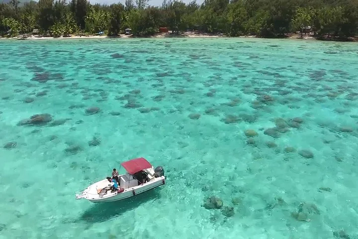 Aerial view of a small motorboat over a lagoon dotted with coral heads