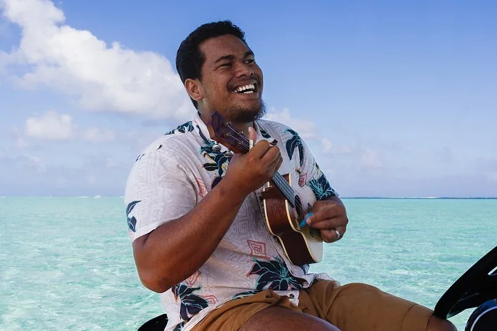 Smiling guide playing ukulele on the boat over shallow lagoon water