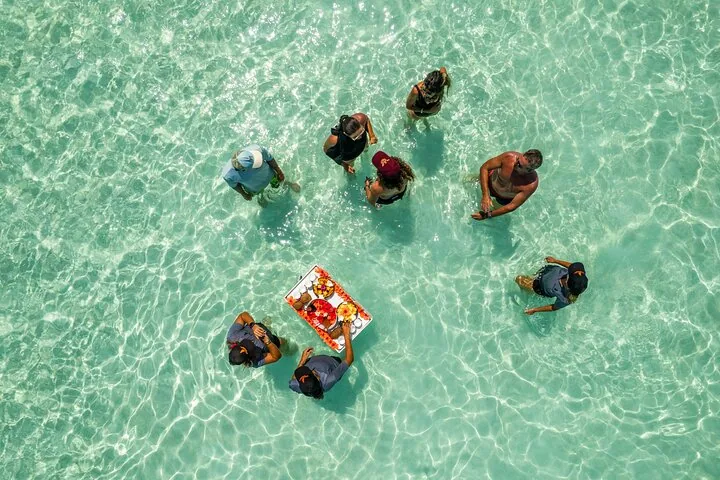 Aerial view of guests standing in clear shallows around a floating tray