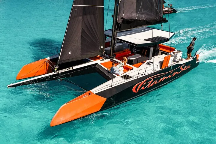 Orange and black catamaran under sail seen from above
