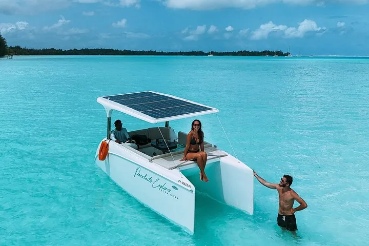 Guests on the solar catamaran deck and standing in waist-deep water