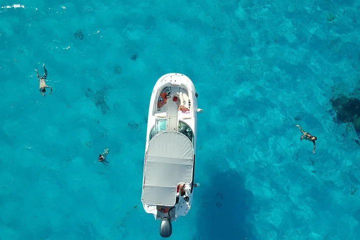 Overhead view of a white boat with snorkelers floating nearby