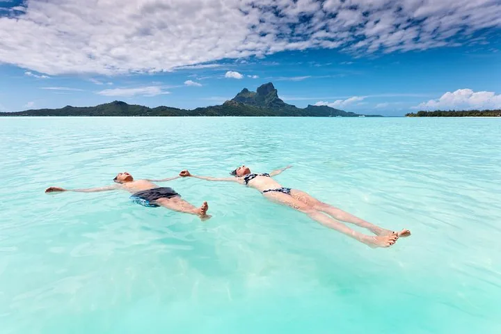 Two people floating on their backs in shallow turquoise lagoon water