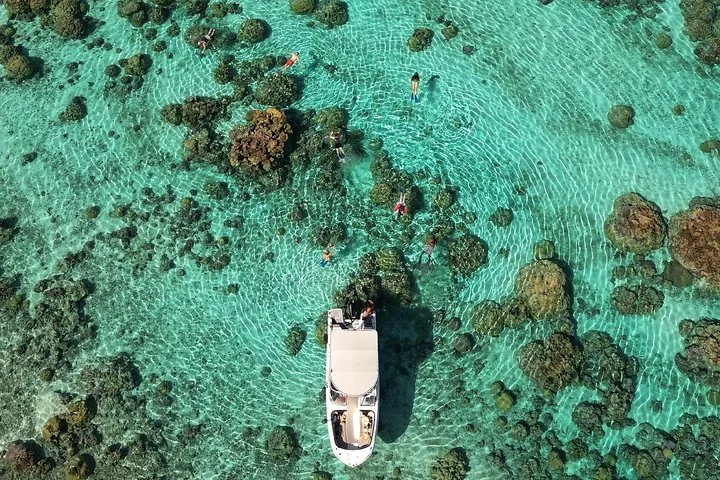 Aerial view of a boat anchored among coral heads with snorkelers