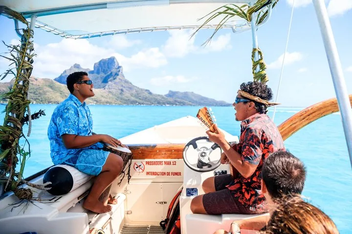 Two Polynesian guides talking at the boat helm with Mount Otemanu behind