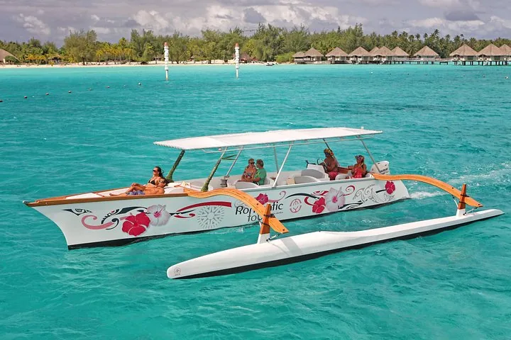 Outrigger canoe with a shade roof cruising past overwater bungalows