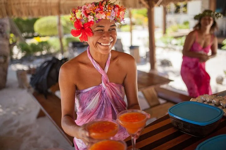 Smiling host in a flower crown serving drinks at the motu lunch