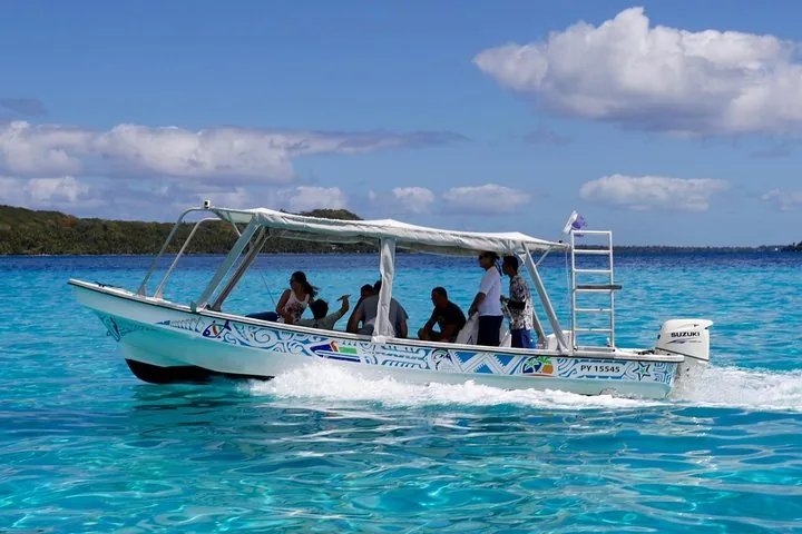 Small covered motorboat with guests crossing turquoise lagoon water